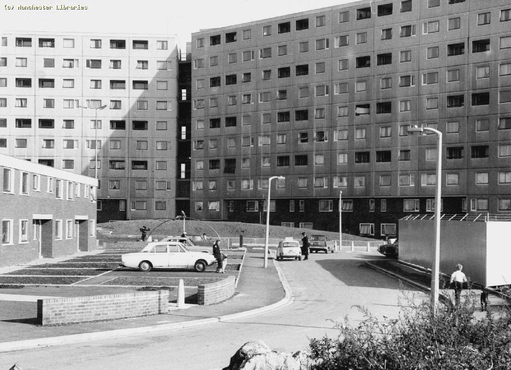 Black and white shot of Ringbeck Crescent flats with cars and policeman.
