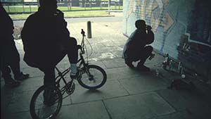 Man on BMX and man doing graffiti in subway.