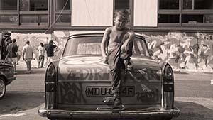 Boy sitting on car boot