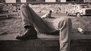 Man wearing jeans lying on back holding can of lager on chest.