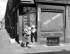 Black and white shot of children standing at Hugh Woods shop front.